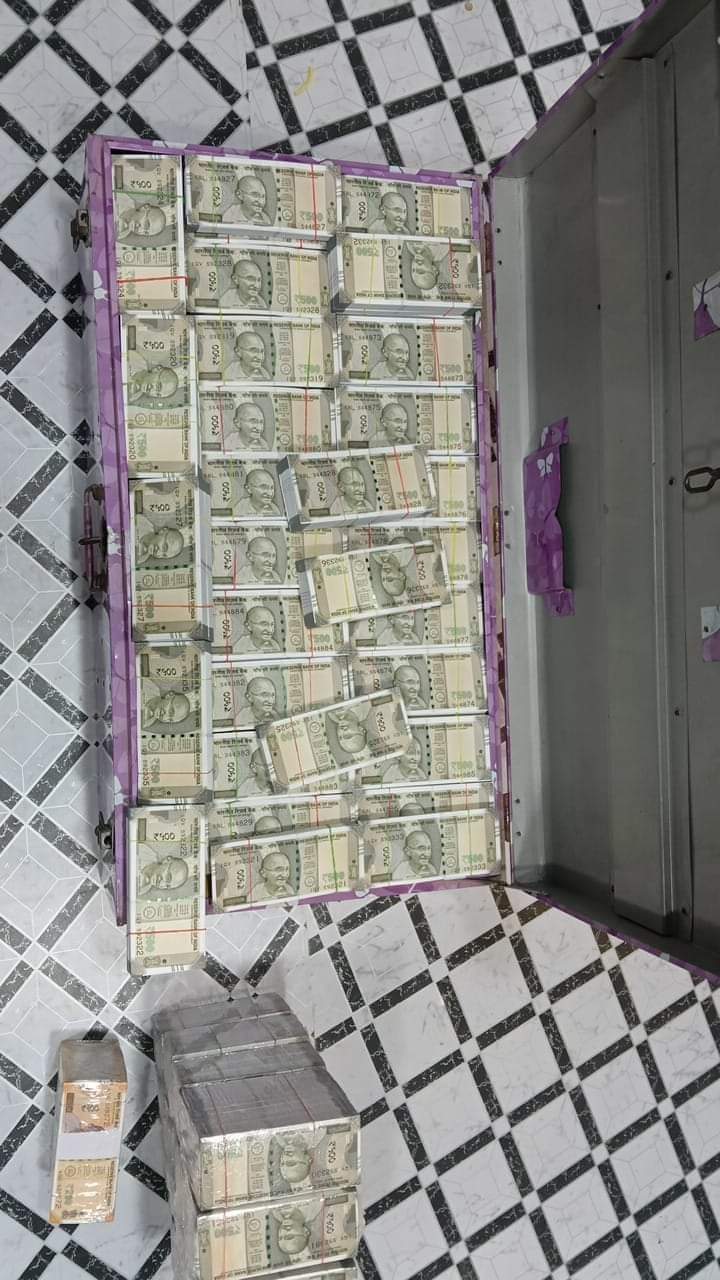 Stacks of Indian 500-rupee notes filling an open purple trunk on a tiled floor.